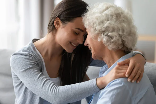 Adulto nieta tacto frentes abrazos anciano abuela disfrutar tierno momento — Foto de Stock