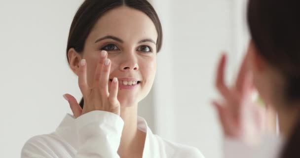 Joven feliz bonita mujer aplicando crema hidratante . — Vídeos de Stock