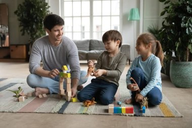 Oyuncu baba evde küçük çocuklarla oynuyor.