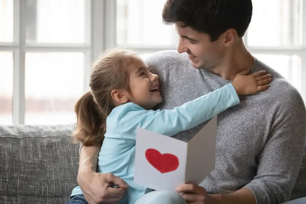 Küçük kız, heyecanlı babayı kartpostalla selamlıyor. — Stok fotoğraf