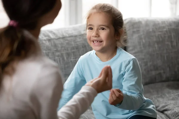 Маленька дівчинка робить жест для рук, щоб вивчити мову жестів з мамою — стокове фото