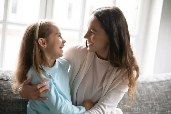 Happy young mom and little daughter hug on couch — Stock Photo, Image