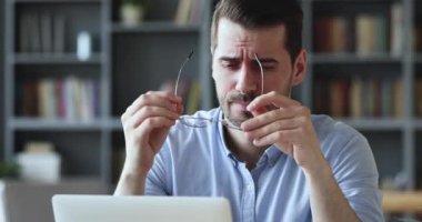 Stressed young man in glasses suffering from muscles tension.