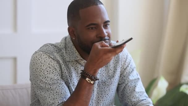 Чорний чоловік говорить з помічником віртуального розпізнавання голосу на смартфоні — стокове відео