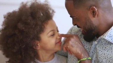 Loving african father playing embracing cute funny little child daughter