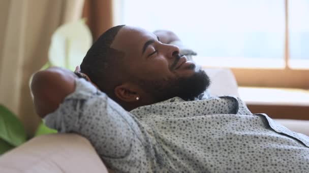 Спокойный ленивый африканский мужчина дремлет, дыша свежим воздухом на диване. — стоковое видео