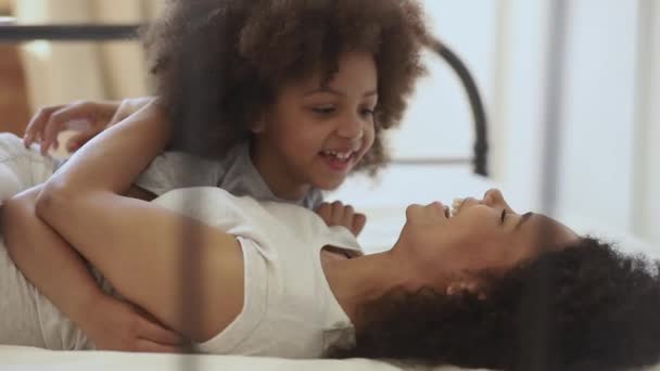 Милый маленький африканский ребенок дочь щекочет счастливую мать на кровати — стоковое видео