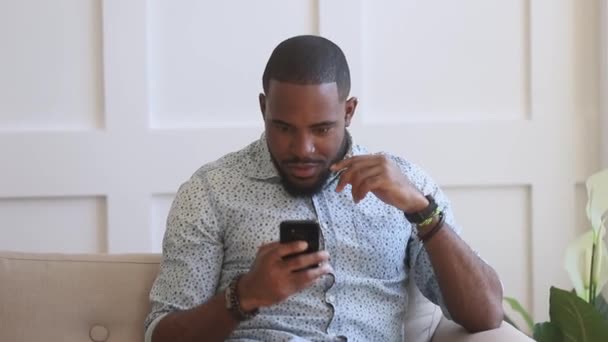 Sorprendido hombre negro emocionado mantenga teléfono inteligente leer buenas noticias de Internet — Vídeo de stock