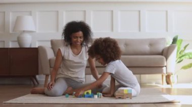 Happy little african kid daughter and mother playing on floor
