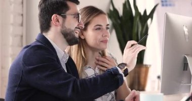 Smart leader explaining corporate software on computer to focused trainee.