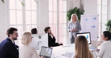 Young multiracial specialists discussing educational lecture with skilled older speaker.