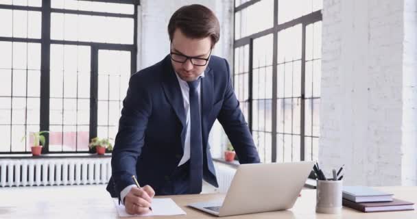 Ejecutivo masculino joven cualificado inteligente que gestiona las tareas en el lugar de trabajo . — Vídeo de stock