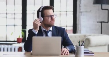 Happy relaxed 30s businessman enjoying break time, listening to music.