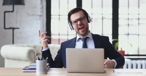 Overjoyed young funny businessman listening to energetic rock music. — Stock videók