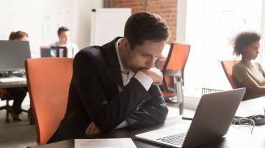 Serious businessman employee using laptop, working on difficult project