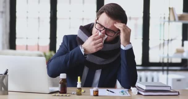 Unhealthy young businessman sitting at workplace covered with warm scarf, — Stockvideo