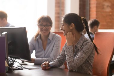 Smiling businesswoman mentor teaching employee, learning new software