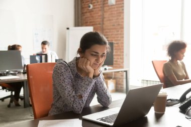 Unhappy Indian businesswoman intern using laptop, looking at screen