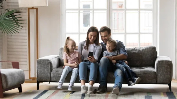 Família feliz com crianças se divertindo com smartphone — Fotografia de Stock