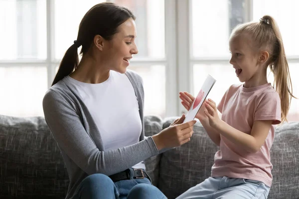 Linda niña felicitando a la madre sonriente, dando tarjeta de felicitación —  Fotos de Stock