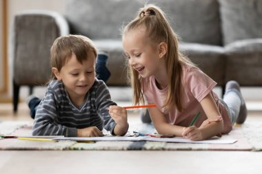 Happy little girl and boy drawing, playing on warm floor