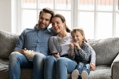 Happy young parents with little son watching tv together