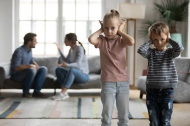 Unhappy little kids covering ears, suffering from parents argument