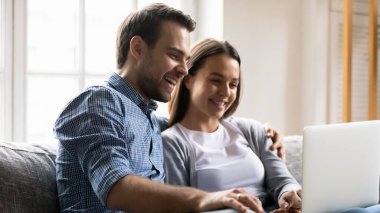 Happy young couple having fun with laptop together