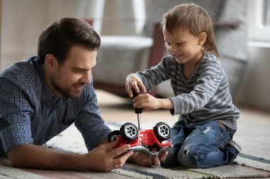 Happy father and little son playing with toy car together