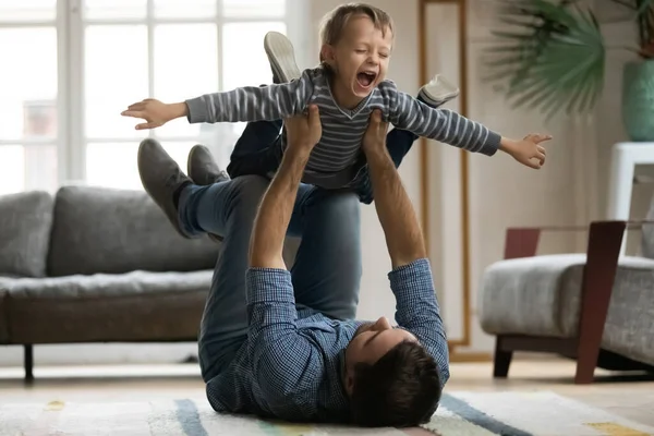 Laughing little boy pretending flying, playing with happy father — 图库照片