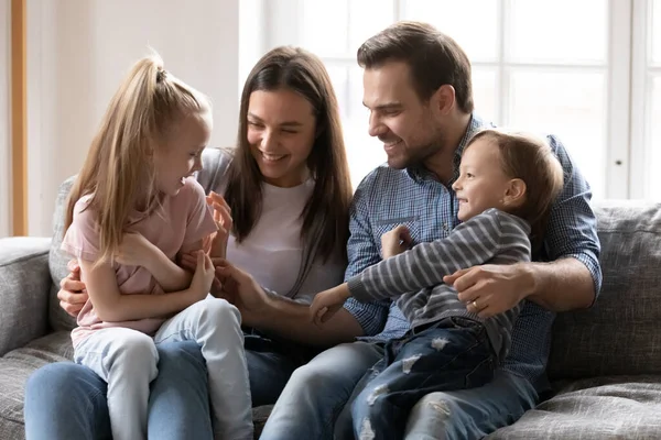 Mère et père souriants s'amusent avec les enfants sur le canapé — Photo