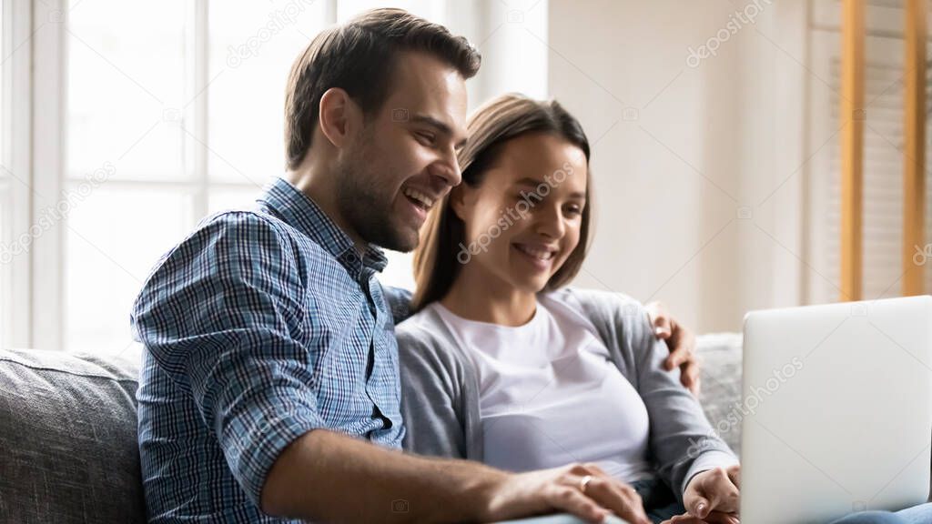 Happy young couple having fun with laptop together