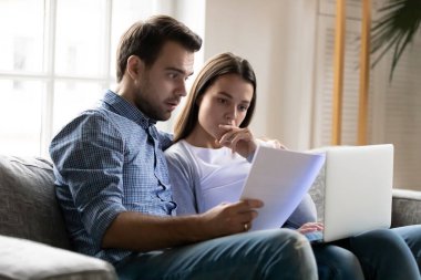 Shocked worried young couple reading documents, financial problems