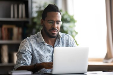 African man sitting at desk using laptop do remote work