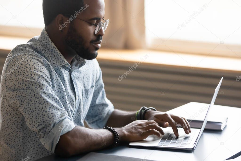 Focused african businessman working on laptop seated at desk