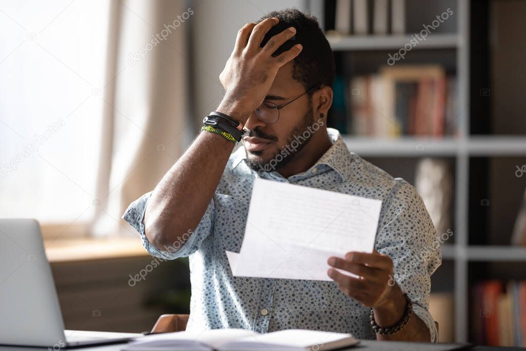 African businessman holding letter reading bad bank news about debt