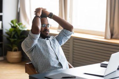 African man leaned on office chair resting looking at pc