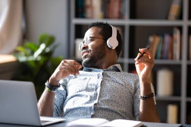 African guy wear headphones listening music enjoy break at workplace