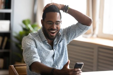 African man holding smartphone read unbelievable news feels excited