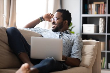 Single guy resting on couch in living room with notebook
