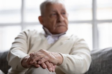Close up thoughtful older man sitting with folded hands