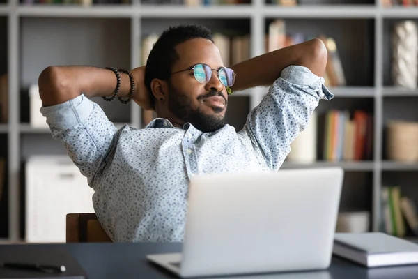 African businessman stretch in office chair looking out the window