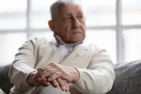 Закройте задумчивого пожилого человека, сидящего со сложенными руками — стоковое фото