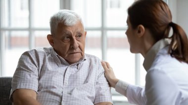 Female doctor comforting upset older patient at meeting