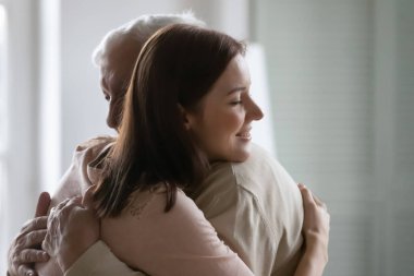 Smiling young woman hugging older man, enjoying tender moment