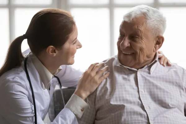 De cerca cuidando doctora hablando con un hombre mayor sonriente — Foto de Stock