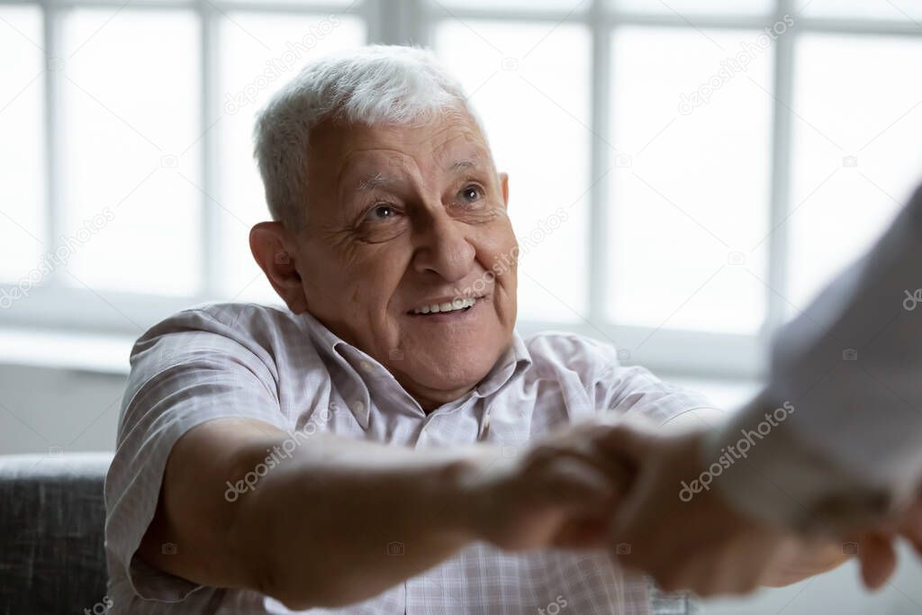 Close up smiling older man holding doctor hands