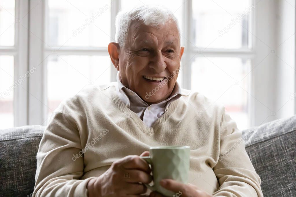 Head shot happy smiling mature man holding cup of tea