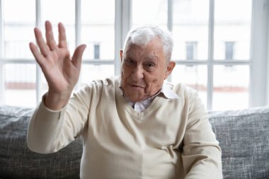 Head shot portrait happy mature man waving hand at camera