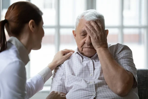 Female doctor comforting older man patient feeling unwell — Stockfoto